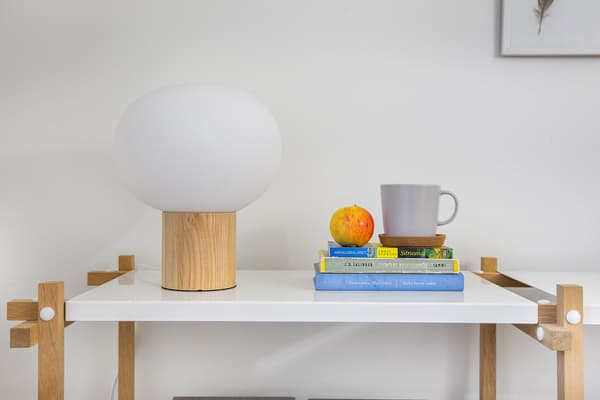 På ett avlastningsbord står en lampa, böcker, kaffekopp och äpple.